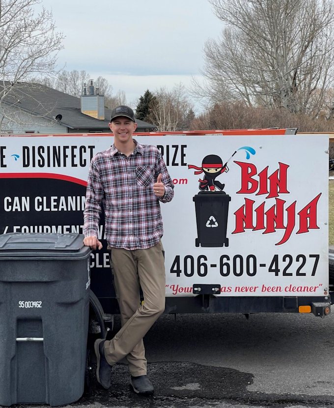 A Bin Ninja team member standing beside the service trailer with a freshly cleaned wheelie bin