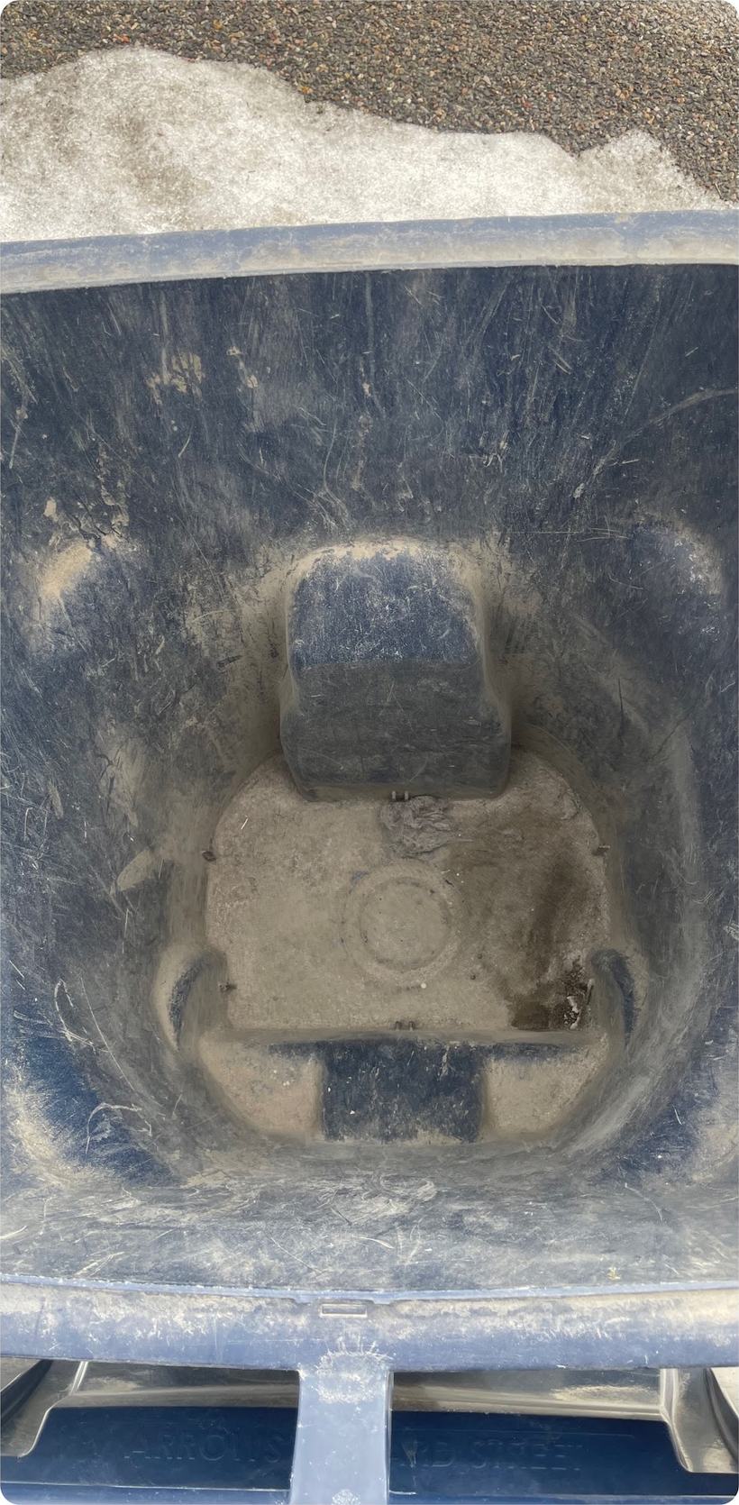 A grimy wheelie bin interior before hot-water cleaning